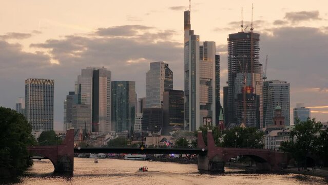 Wide clip of the Frankfurt skyline at sunset taken from Ignatz Bubis Bridge. The city lights are beginning to come on 