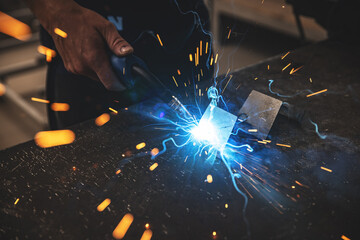 Male worker hand welding steel rack - obrazy, fototapety, plakaty