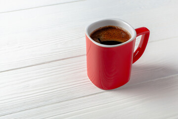 A red cup of strong coffee on white table. Red mug with coffee