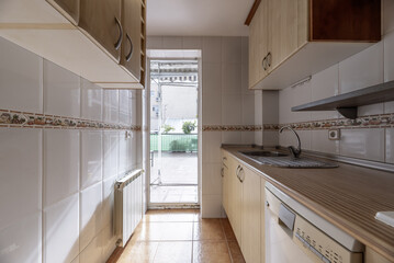 Fototapeta na wymiar Kitchen in a tube-type room with cabinets on both sides and access to a large terrace