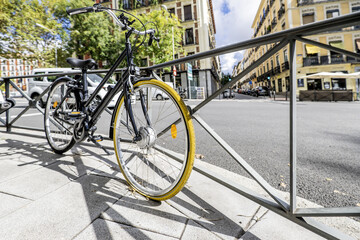 Fototapeta na wymiar A black touring bicycle with a yellow-covered front wheel