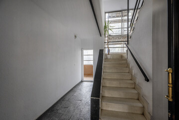 Interior stairs of an urban residential building with access to an interior patio and with scaffolding on the façade