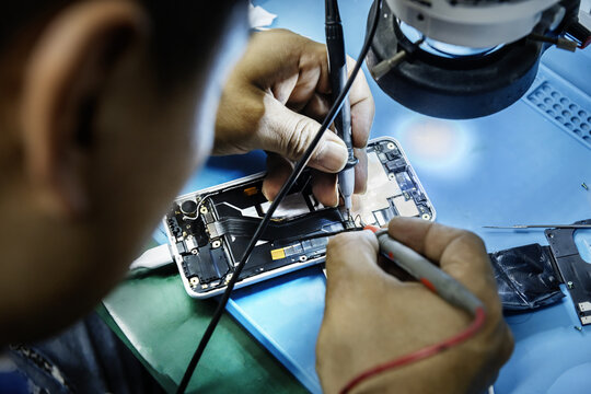 A technician repairing a mobile phone at his work table