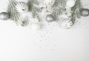 Christmas composition, white and silver decorations, fir tree branches, white flowers, silver stars confetti on white background. Christmas, New Year, winter concept. Top view, flat lay, copy space. 