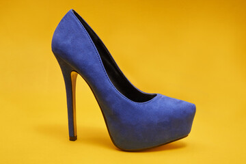 Blue velour high heel shoes on a yellow background
