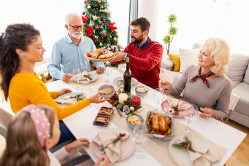 Family gathered around the table having Christmas dinner together at home