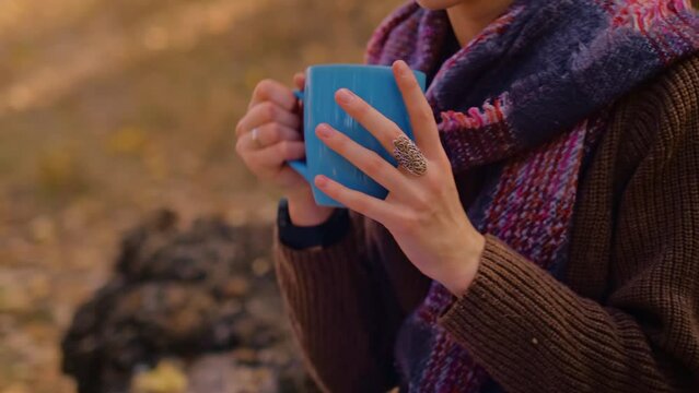 woman with a backpack drinks tea from a cup, dressed in a brown sweater, holds a map in her hands, enjoys sunny weather in the autumn forest, traveler on the precipice, My Real Holiday, MyRealHoliday