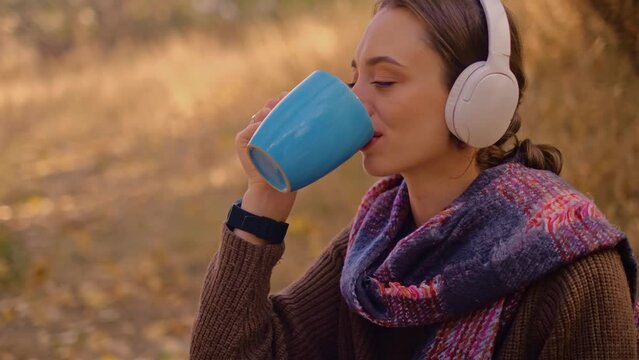 woman with a backpack drinks tea from a cup, dressed in a brown sweater, holds a map in her hands, enjoys sunny weather in the autumn forest, traveler on the precipice, My Real Holiday, MyRealHoliday