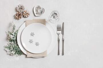 Festive table setting with Christmas silver decorations on white background. New Year serving with a copy space. Copy space, top view, flat lay.