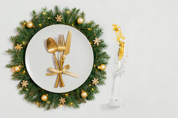 Festive table setting with Christmas wreath and golden decorations on white background with copy space. Happy new year. Space for text. Top view, flat lay.