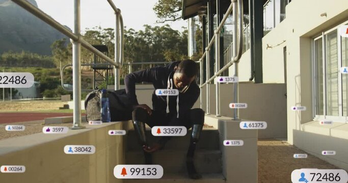 Animation of social media icons over african american man adjusting his prosthetic leg at stadium