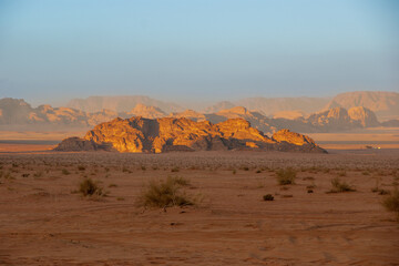 Naklejka premium Jordan. Desert of Wadi Rum. Bizarre shapes of rocks in deserted desert. Landscape is similar to Martian landscapes. Sand is of beautiful pink color in rays of setting sun. Nature concept for design.
