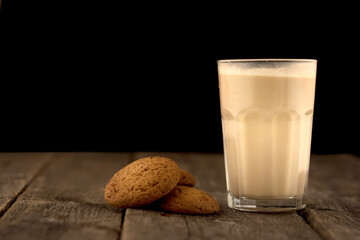Tasty cookies and glass of milk on rustic wooden background