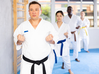 Group of multiethnic people in kimonos train karate techniques in studio