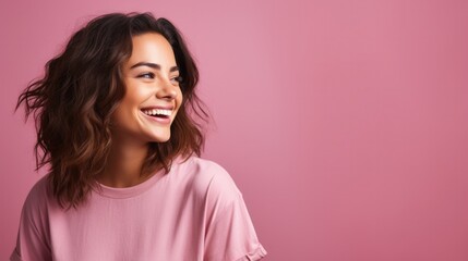 Fototapeta premium Portrait of a young latin woman with pleasant smile and isolated on pink wall with copy space. Beautiful girl with waves hair looking aside against pastel wall. Cheerful hispanic woman