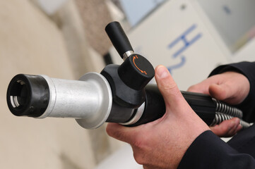 A man holds the high pressure (350 bar) nozzel at a hydrogen fuel filling pump station.