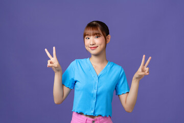 Portrait of funky pretty young person beaming smile finger show v-sign isolated on purple background