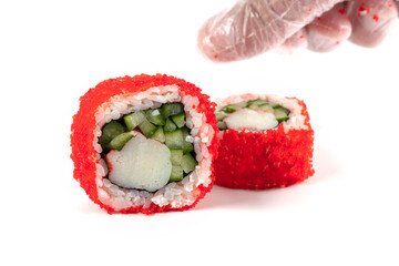 Sushi rolls boned in red artificial caviar on a white background close-up with a hand in culinary gloves.