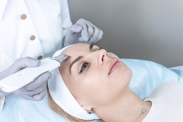 Naklejka premium A dermatologist does an ultrasound facial peeling for a beautiful woman.