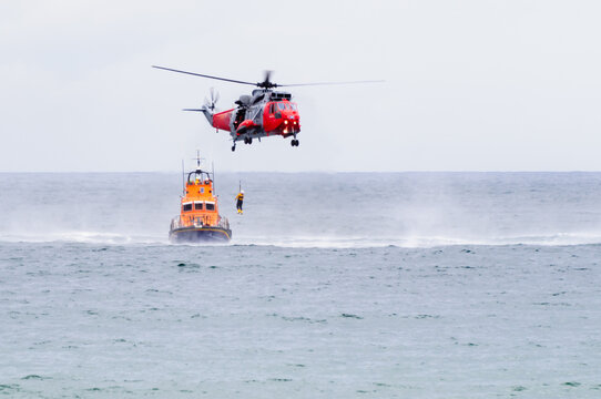 A helicopter winches a man on board as the RNLB lifeboat waits.