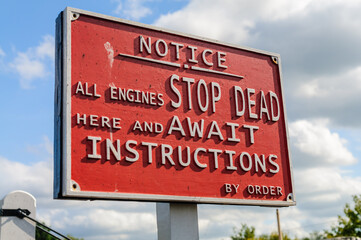 Sign on a railway instructing drivers to stop dead and await instructions