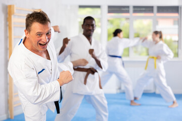 Fototapeta na wymiar Irate middle-aged male karate practitioner fighting with his opponent in sports hall