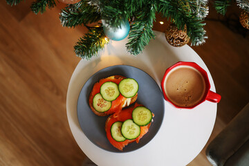 Christmas snack. A light fir tree next to sandwiches and a red cup of coffee