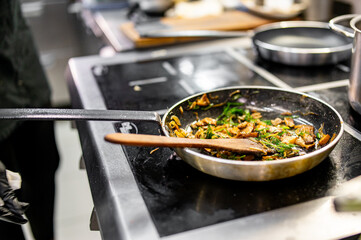 chef hold pan with mushroom and onion at the restaurant kitchen