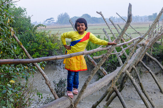Portrait of a young Bangladeshi girl standing on a bamboo bridge 