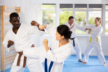 Fototapeta na wymiar Active middle-aged man attendee of karate classes practicing fighting techniques during workout session