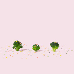 Broccoli with confetti on a pink background. Creative food concept.