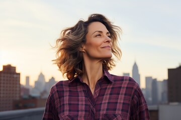 Portrait of a blissful woman in her 40s wearing a comfy flannel shirt against a stunning skyscraper skyline. AI Generation