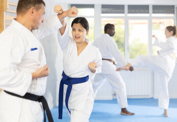 Fototapeta na wymiar In gym, cosmopolite athletes work in pairs and learn to use classic karate techniques to repel an opponents blow, hone melee skills, strengthen spirit. Sport as lifestyle.