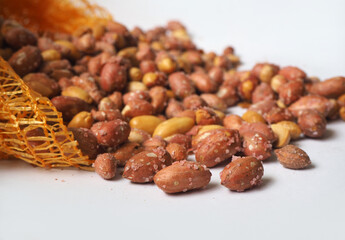 Salted roasted peanuts spilling from the sack. Pile of groundnut. Selected focus.
