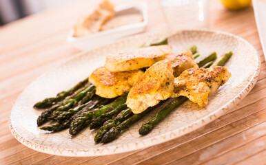 Fried chicken breast pieces with asparagus on white plate