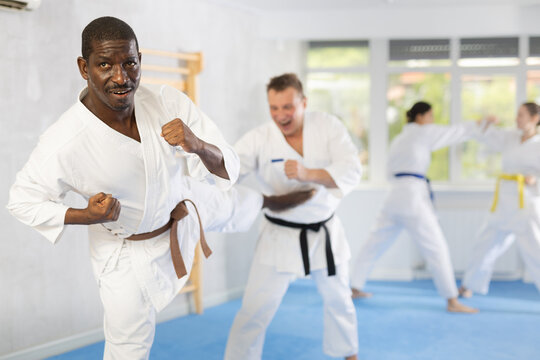 Two adult male judokas practicing judo technique in group in gym