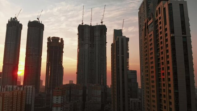 Silhouette View of sunset behind Modern City high-rise skyscraper buildings in Mumbai City, beautiful yellow evening shot. 4k