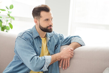Fototapeta premium Photo portrait of brunet sitting on sofa wearing jeans outfit smiling looking blank space relaxing at home