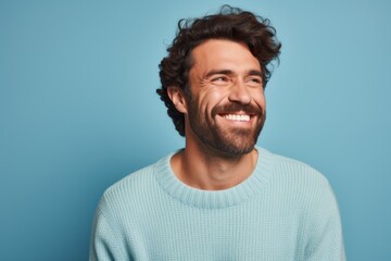 Obraz premium Portrait of a happy man in his 30s wearing a cozy sweater against a pastel blue background. AI Generation