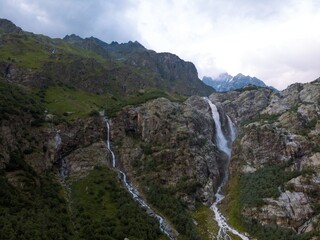 Aerial panorama of a Ushbi Waterfall among the Caucasian mountains, Stormy flow of mountain river Dolra. Summer vacation, hiking in Georgia