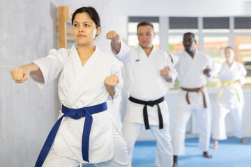 Fototapeta na wymiar Multinational athletes starting position and studying and repeating sequence of punches and painful techniques in karate kata technique. Oriental martial arts, training and obtaining black belt