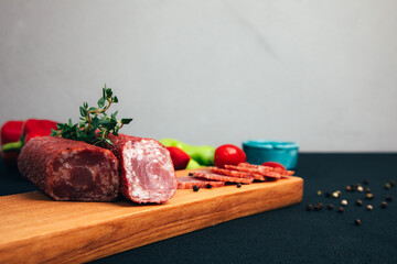 Sausage of different types and sizes on a wooden tray with green paper and tomatoes. Set of smoked...