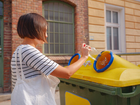 woman throwing plastic bottle Recycling bin stand on european street. Waste separation rubbish before drop to garbage bin to save world, environment care. Pollution trash recycling management concept