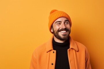 Fototapeta premium Portrait of a cheerful man in his 30s sporting a trendy beanie against a pastel orange background. AI Generation