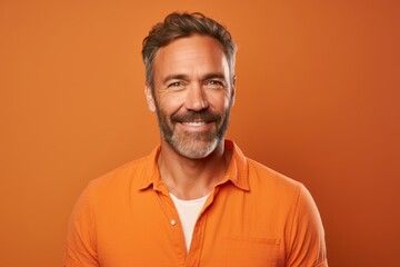 Fototapeta premium Portrait of a blissful man in his 40s wearing a simple cotton shirt against a pastel orange background. AI Generation