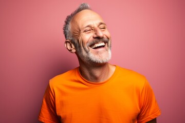 Obraz premium Portrait of a glad man in his 50s sporting a vintage band t-shirt against a pastel orange background. AI Generation