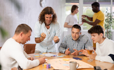 Fototapeta premium Group of active men play board games during a friendly meeting