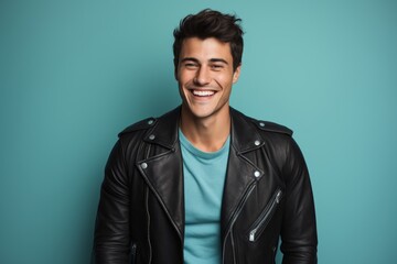 Obraz premium Portrait of a jovial man in his 20s sporting a classic leather jacket against a pastel teal background. AI Generation