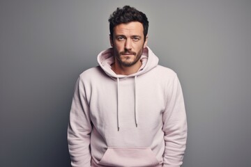 Obraz premium Portrait of a glad man in his 30s sporting a comfortable hoodie against a pastel gray background. AI Generation