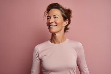 Obraz premium Portrait of a tender woman in her 40s showing off a lightweight base layer against a pastel brown background. AI Generation
